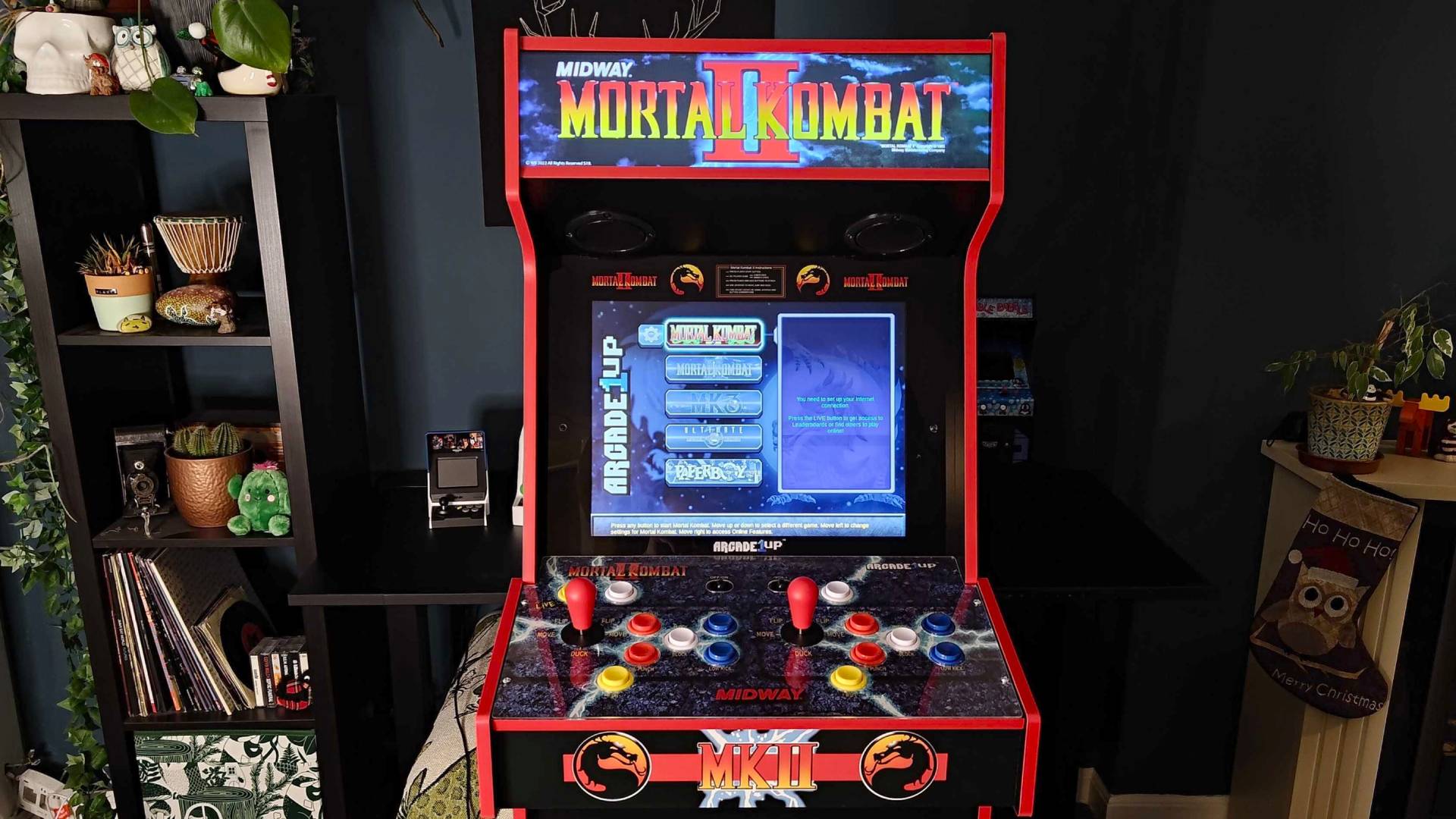 Arcade1Up Mortal Kombat Deluxe machine front view with screen on and menu displayed.