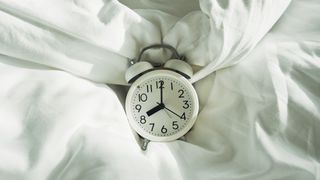 white alarm clock on bed