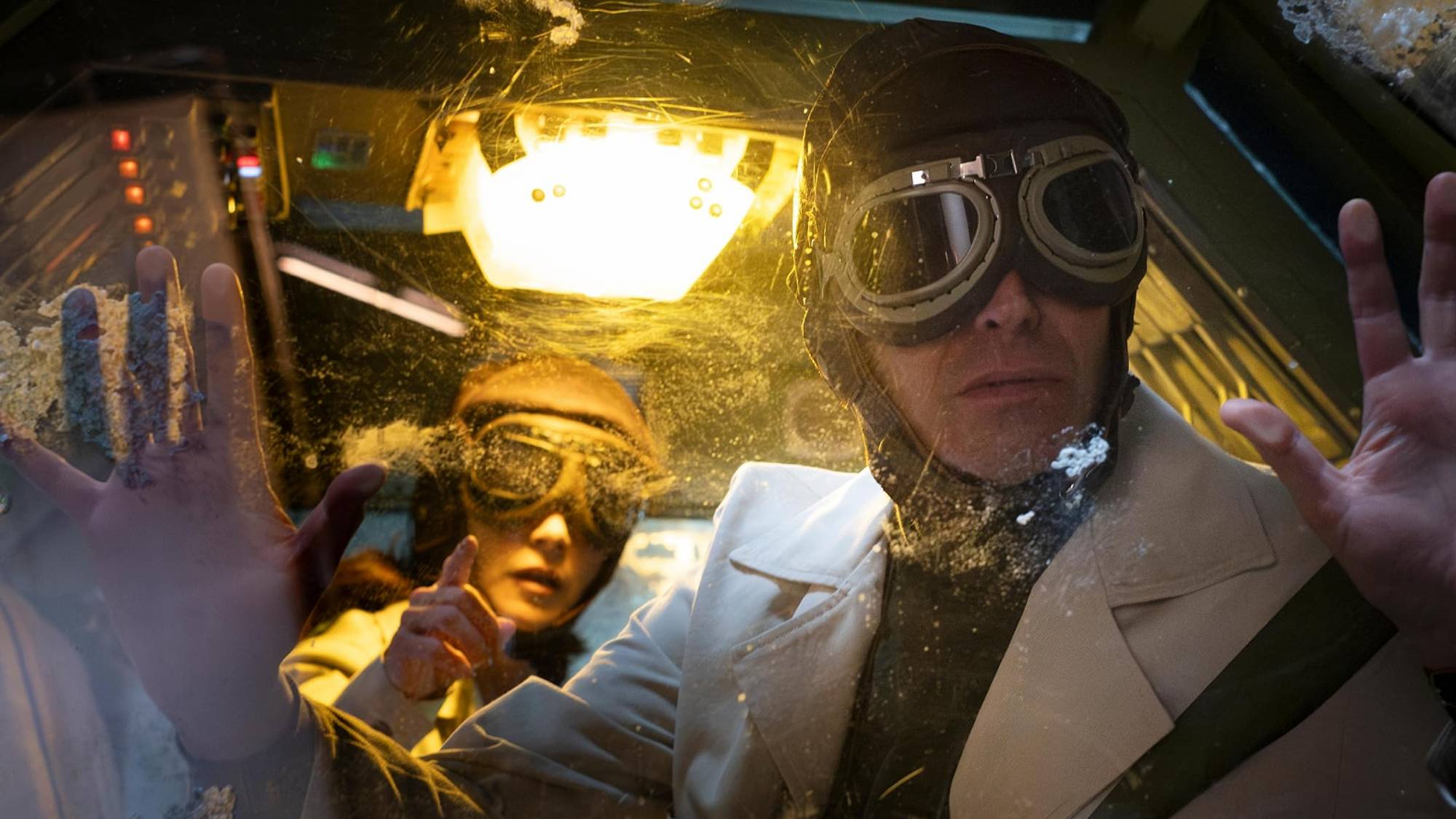 Lucero as Dr. Nora Cervantes and Benny Ibarra as Dr. Héctor Esquivel, both wearing goggles as they stare out of a window surprised in "Our Times" on Netflix