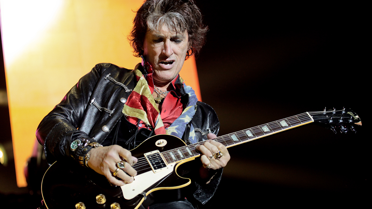 A photograph of Joe Perry on stage with a guitar