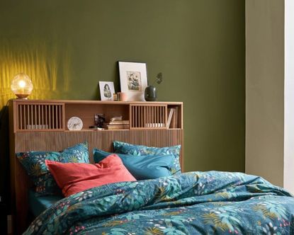 Pilpao Oak Storage Headboard in green bedroom with patterned blue bedding, plants and picture frames
