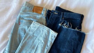 a pair of light blue and dark blue jeans layed next to each other on top of a white sheet