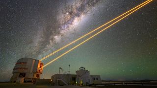 a gray structure in the lower left corner shoots out several lasers that point off into the top right corner. In the background is the Milky Way.