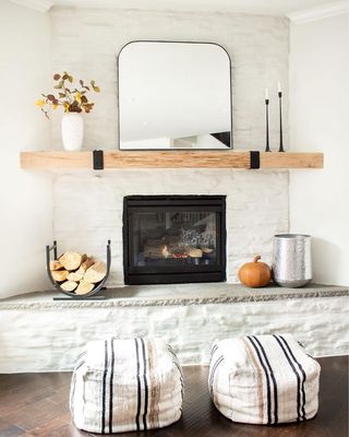 fireplace with wood blocks, a pumpkin and wood mantel with black candlesticks and mirror