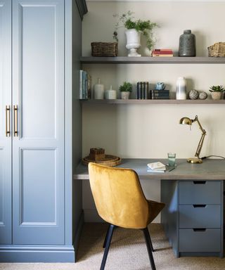 home office area with tall blue cupboard, matching blue desk drawers, desk with matching shelving above, and an orange chair