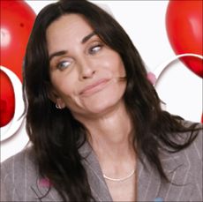 Courteney cox in front of red balloons looking off camera for pop quiz 