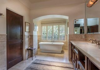 bathroom with bathtub mirror on wall with brown cabinet