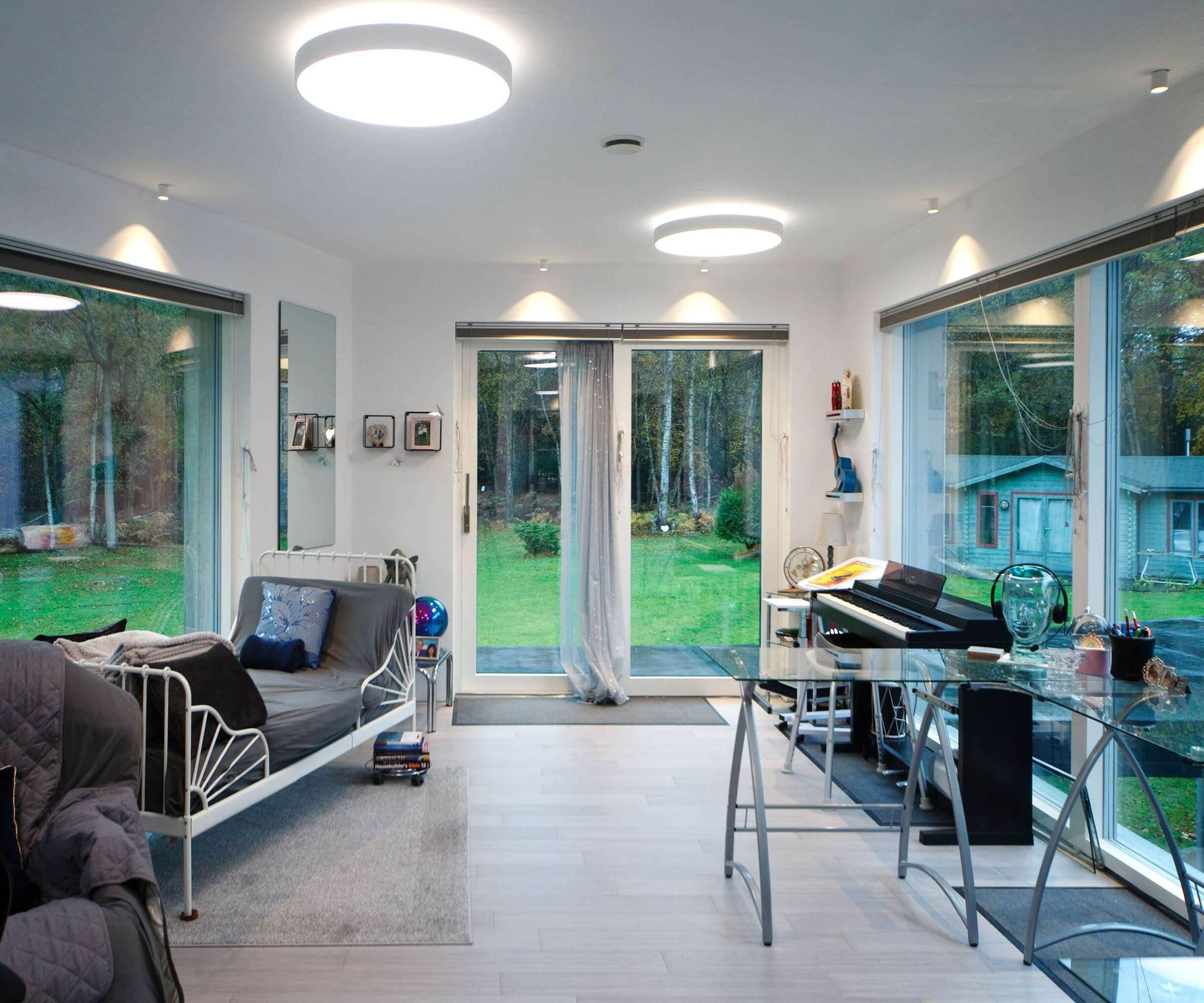 A bedroom office with a piano and floor-to-ceiling windows