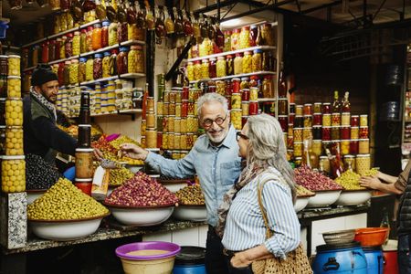 A couple sampling food in a market. 