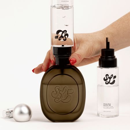 a woman fills a scent lab potion bottle with scent lab body mist in front of a plain backdrop