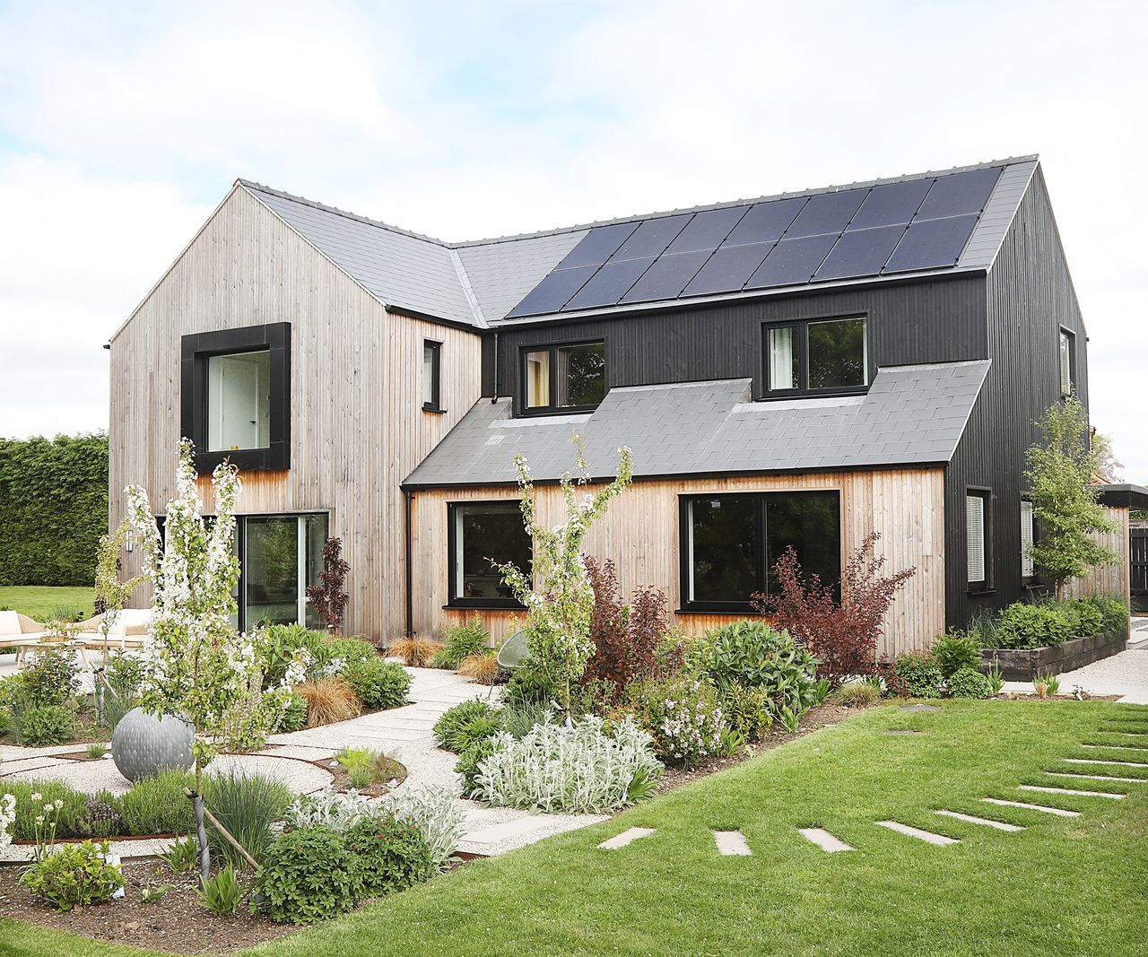 Exterior view of a newly renovated detached home with fully landscaped garden. Clad in timber and black