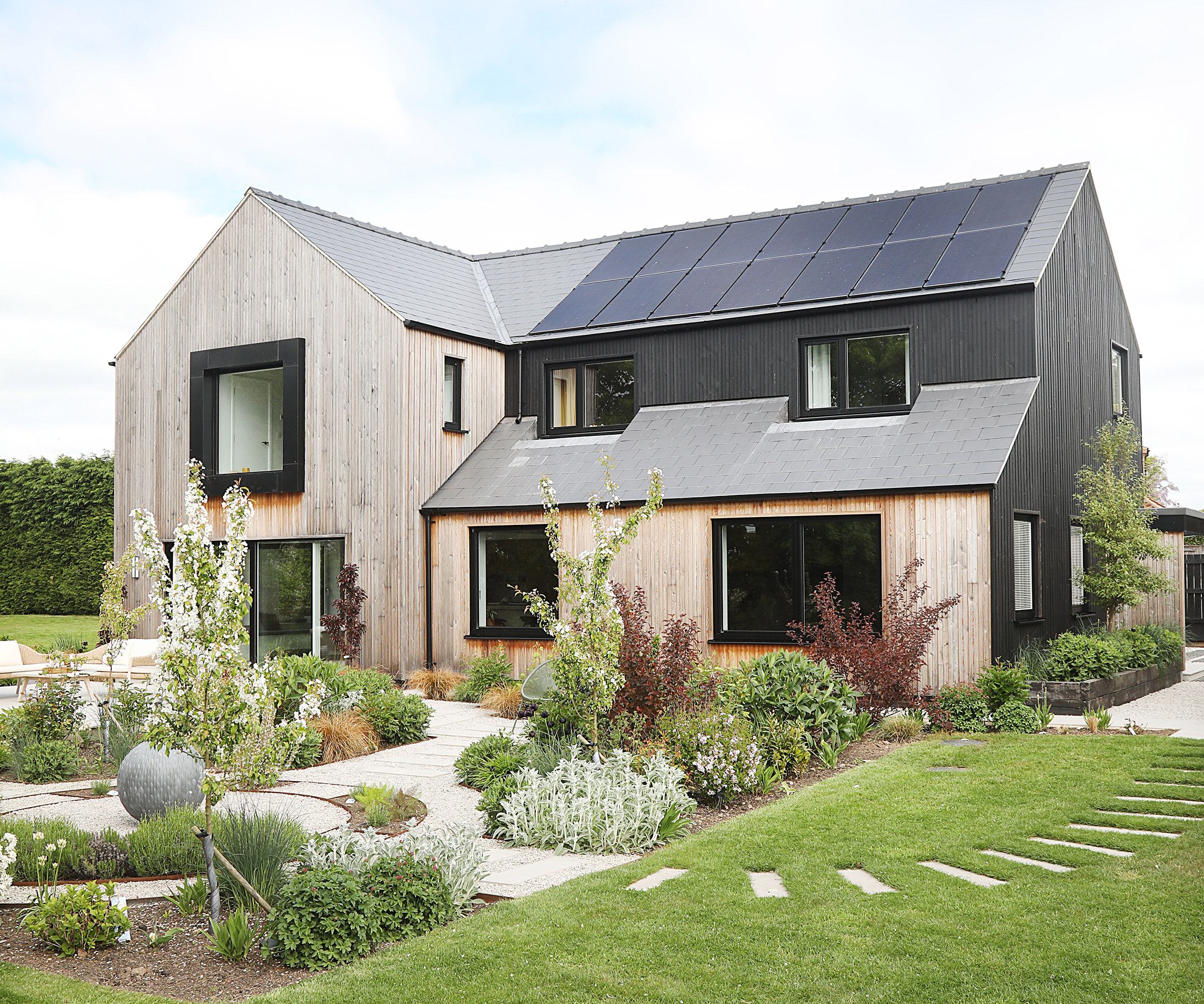 Exterior view of a newly renovated detached home with fully landscaped garden. Clad in timber and black