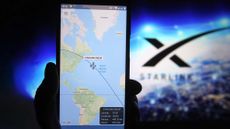 A satellite tracker image is seen displayed on a smartphone with a Starlink logo in the background