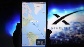 A satellite tracker image is seen displayed on a smartphone with a Starlink logo in the background