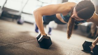 Woman performing a dumbbell push-up during CrossFit style workout