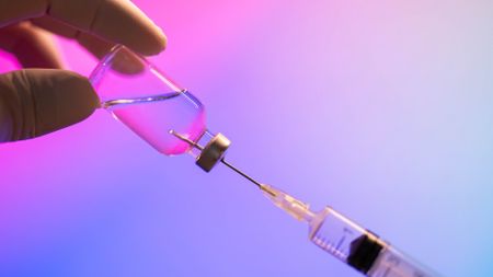 A close-up of a doctor loading a syringe with a dose of a vaccine
