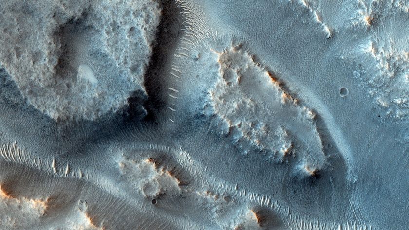 A close up of the surface of Mars showing blue dunes with streaks of ancient river basins between the dunes