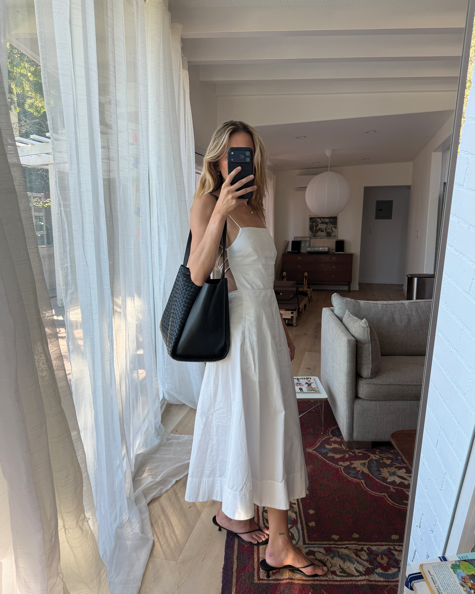 Eliza Huber wearing a white dress, sandals, and the new Bottega Veneta Corso bag.