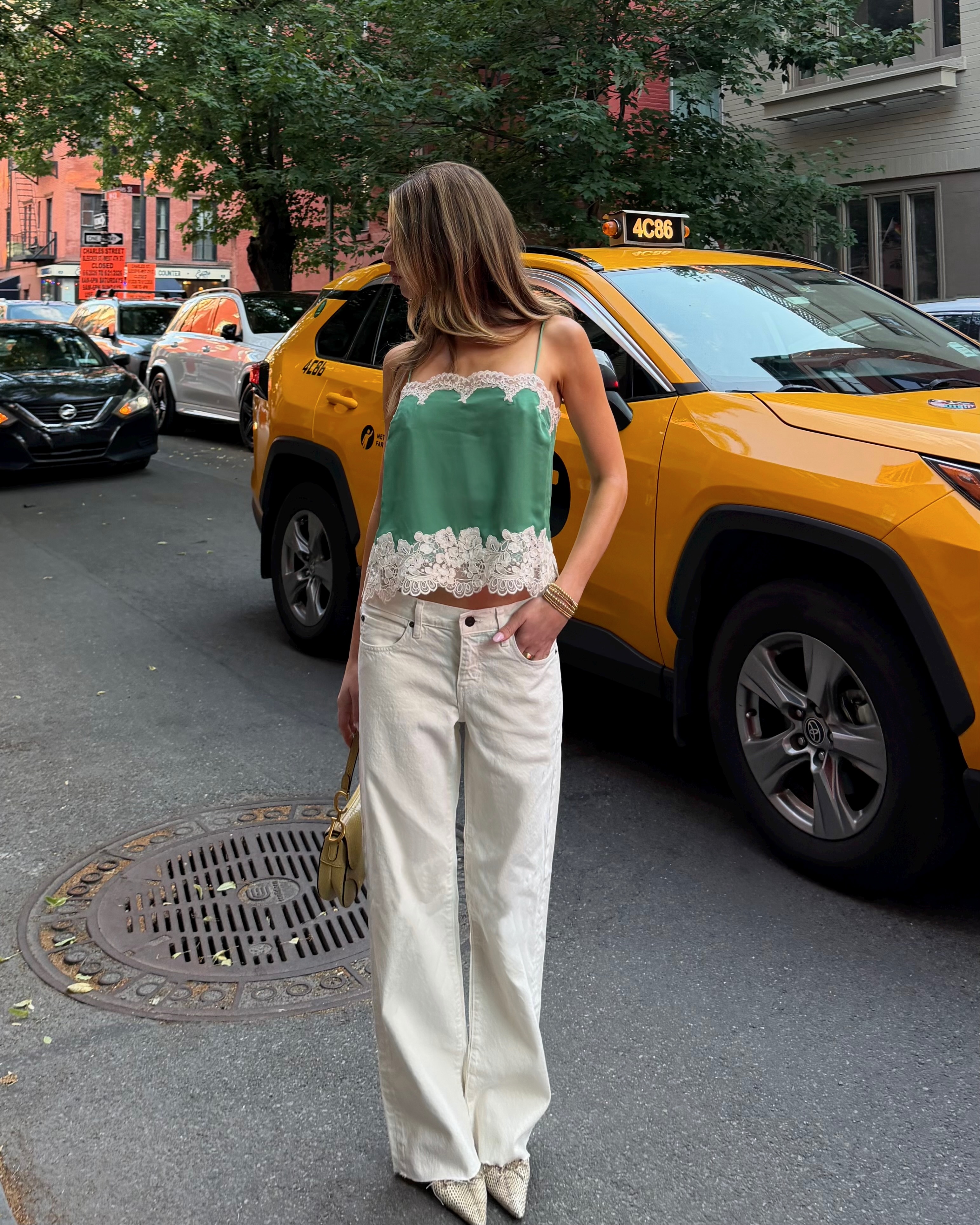 Kit in a green lace camisole and white jeans