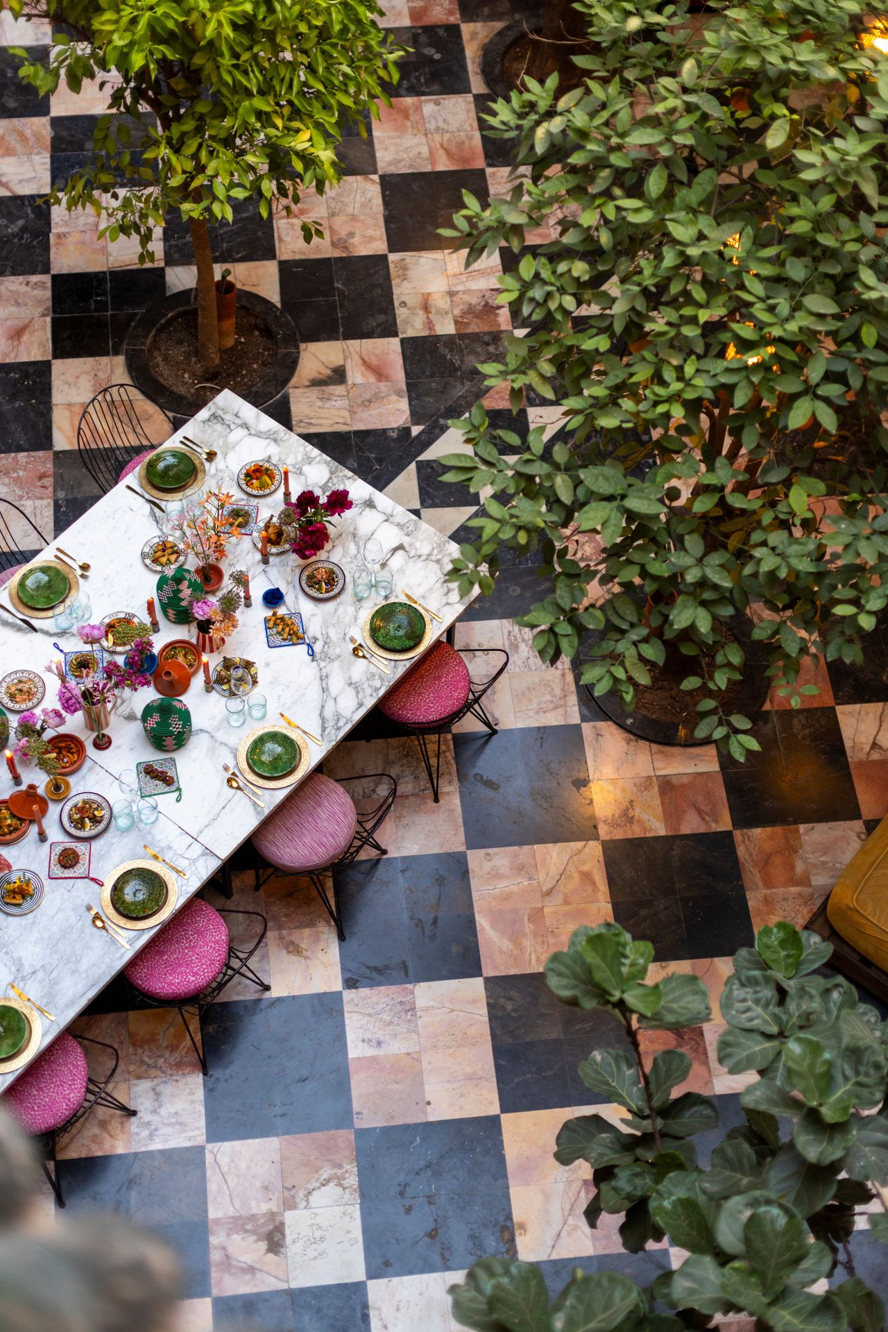 A courtyard with checkered floors, an adorned table, and plants captured from above.