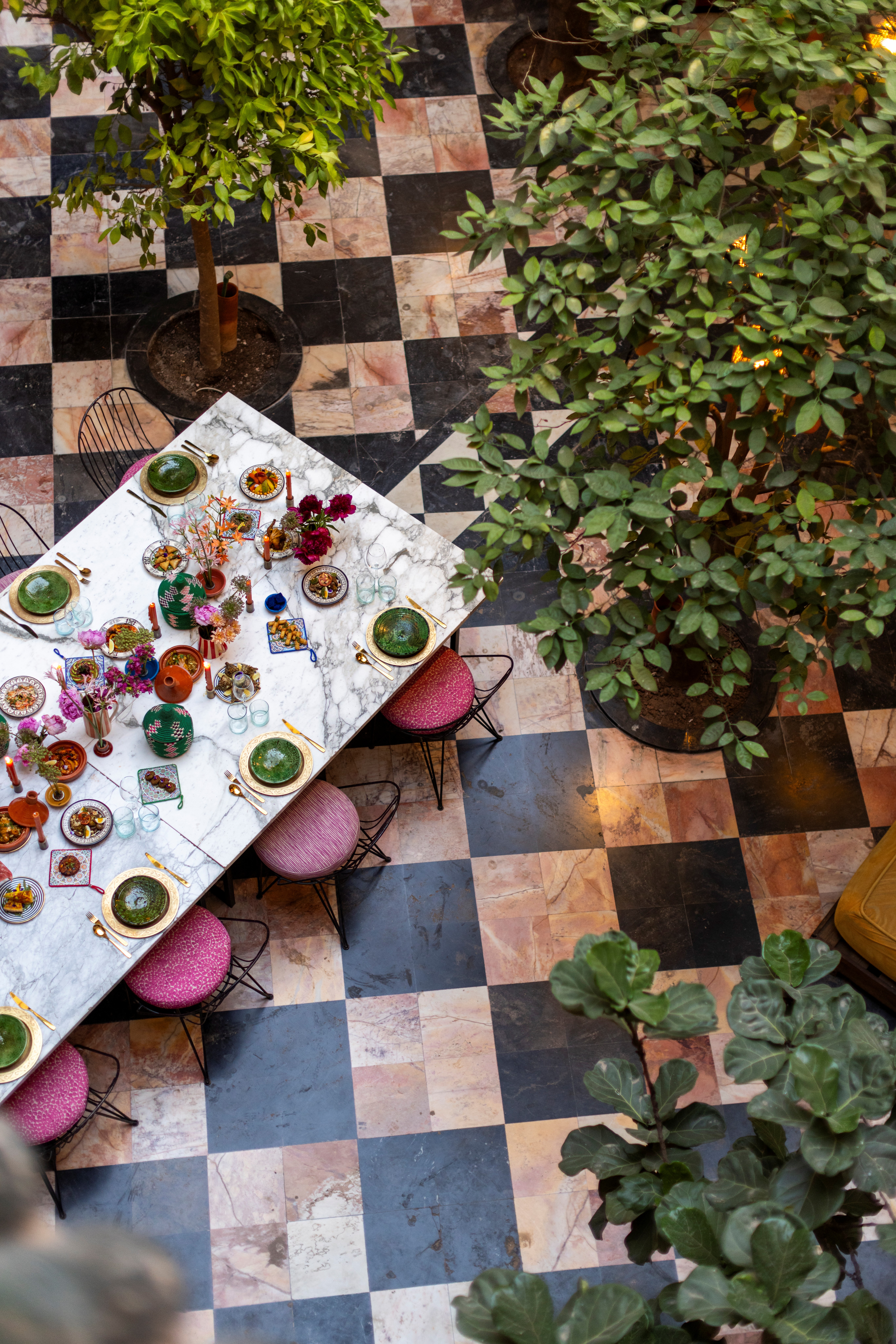 A courtyard with checkered floors, an adorned table, and plants captured from above.