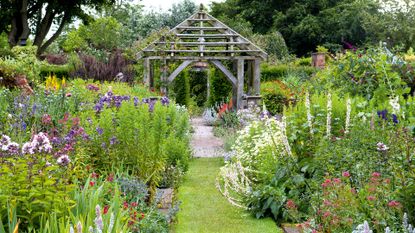 An example of how to plan a garden showing a garden design with cottage borders and a pergola in the center