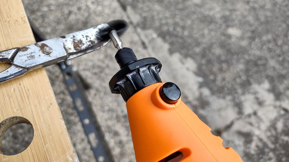 An orange rotary multi tool being used to sharpen some scissors