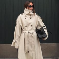 Woman wears trench coat and black bag