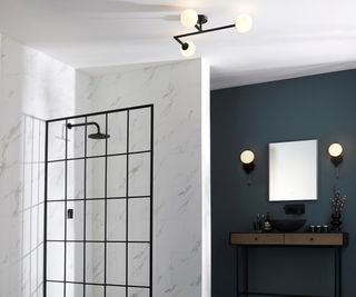 bathroom with angular black ceiling light with three white globe shades and two matching wall lights on blue wall either side of mirror above sink