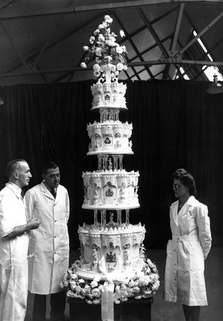 Mr Schur (centre), chief confectioner at McVitie and Price Ltd, standing next to the official cake for Princess Elizabeth's marriage to Philip Mountbatten which is nine feet tall.