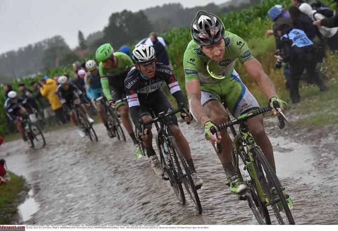 Peter Sagan holds his muddy glasses in his mouth