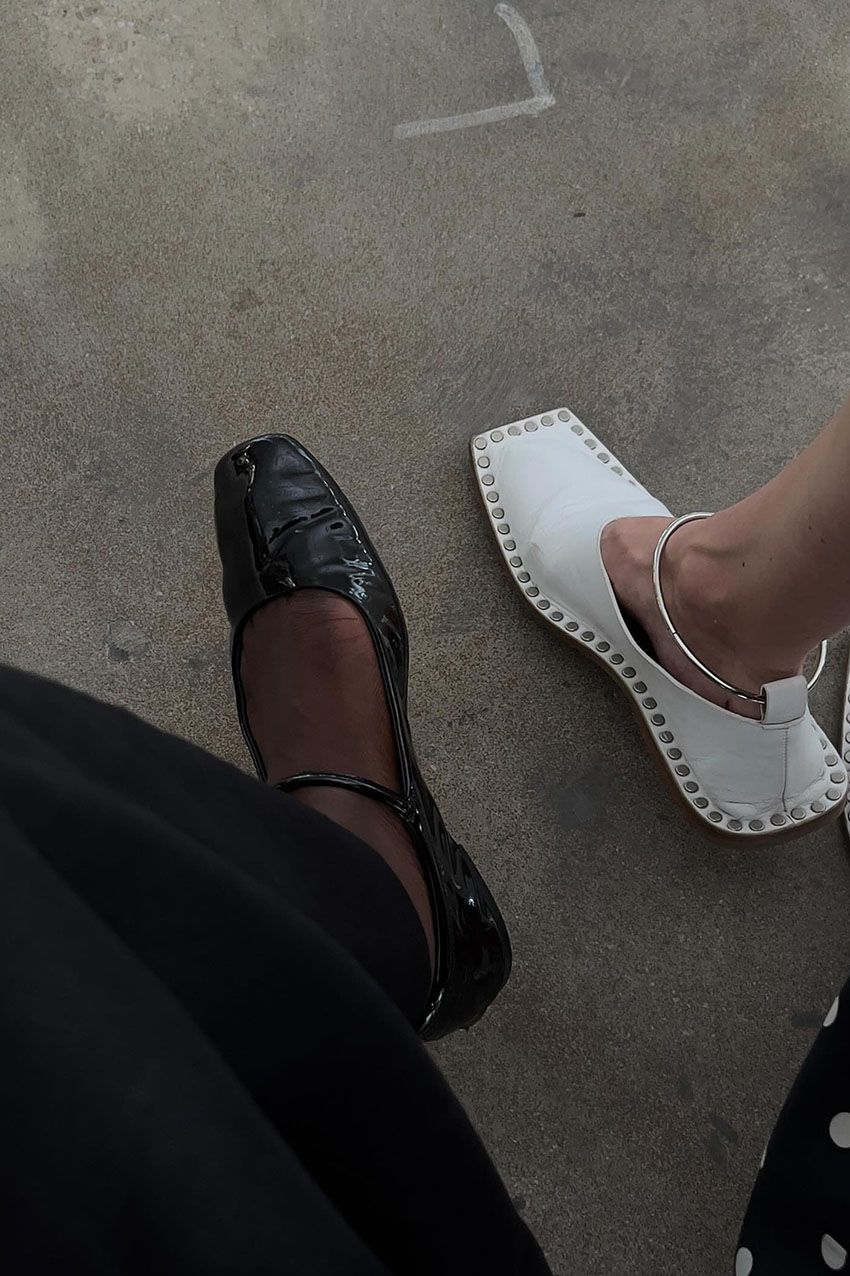 A woman wearing a black skirt and black mary jane flats