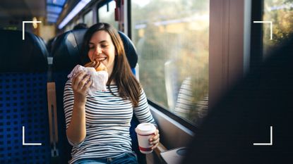 Woman holding pastry and coffee on the train, looking out of the window, smiling after learning how to eat healthy while traveling