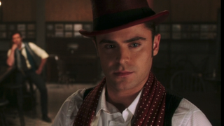 Zac Efron in maroon top hat in The Greatest Showman