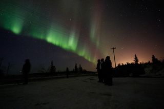 The northern lights blaze in the Alaskan sky in the early morning hours of April 11, 2012, trumping the city lights of nearby Fairbanks (at right).