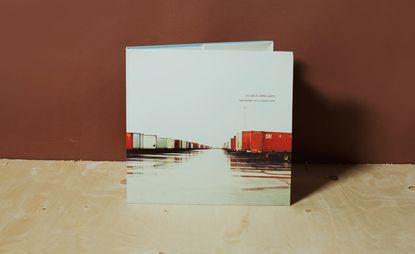 The cover of Taxonomy of a Landscape book featuring a white lorry parking lot with lorries on either side. 
