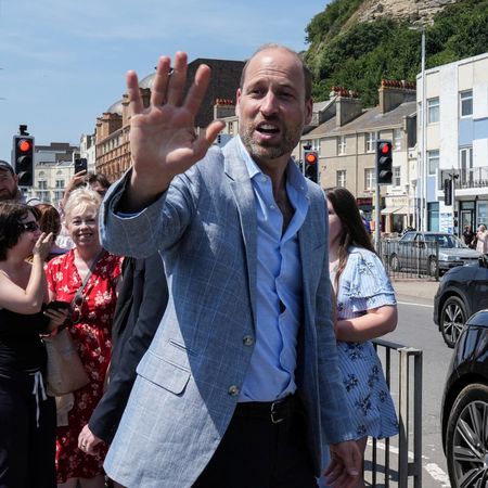 Prince William wears a gray suit jacket, a blue shirt and black slacks to visit Hastings, where he meets children and royal fans on the seafront