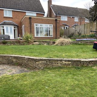 terraced three tier lawn with stone walls and house in shot