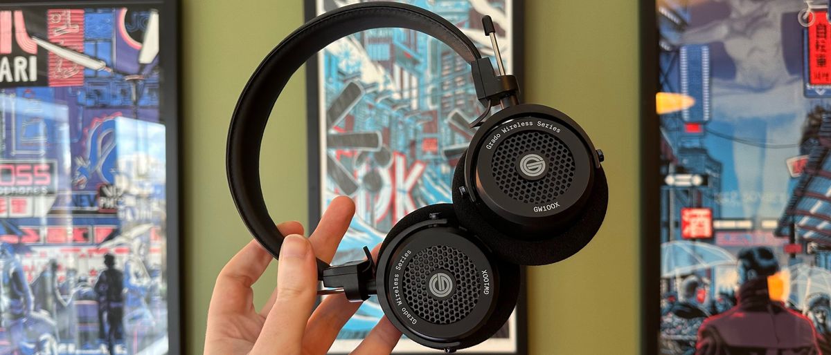 Grado&#039;s GW100x headphones in a green-walled room, on a wooden desk with cutting mat.