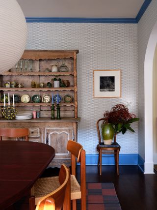 Wallpapered dining room with plates displayed in dresser