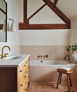 modern rustic bathroom with inbuilt stone surround bath and exposed wooden beams