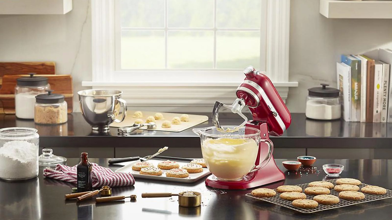 Red KitchenAid stand mixer on a kitchen countertop, surrounded by baking equipment and ingriedients 