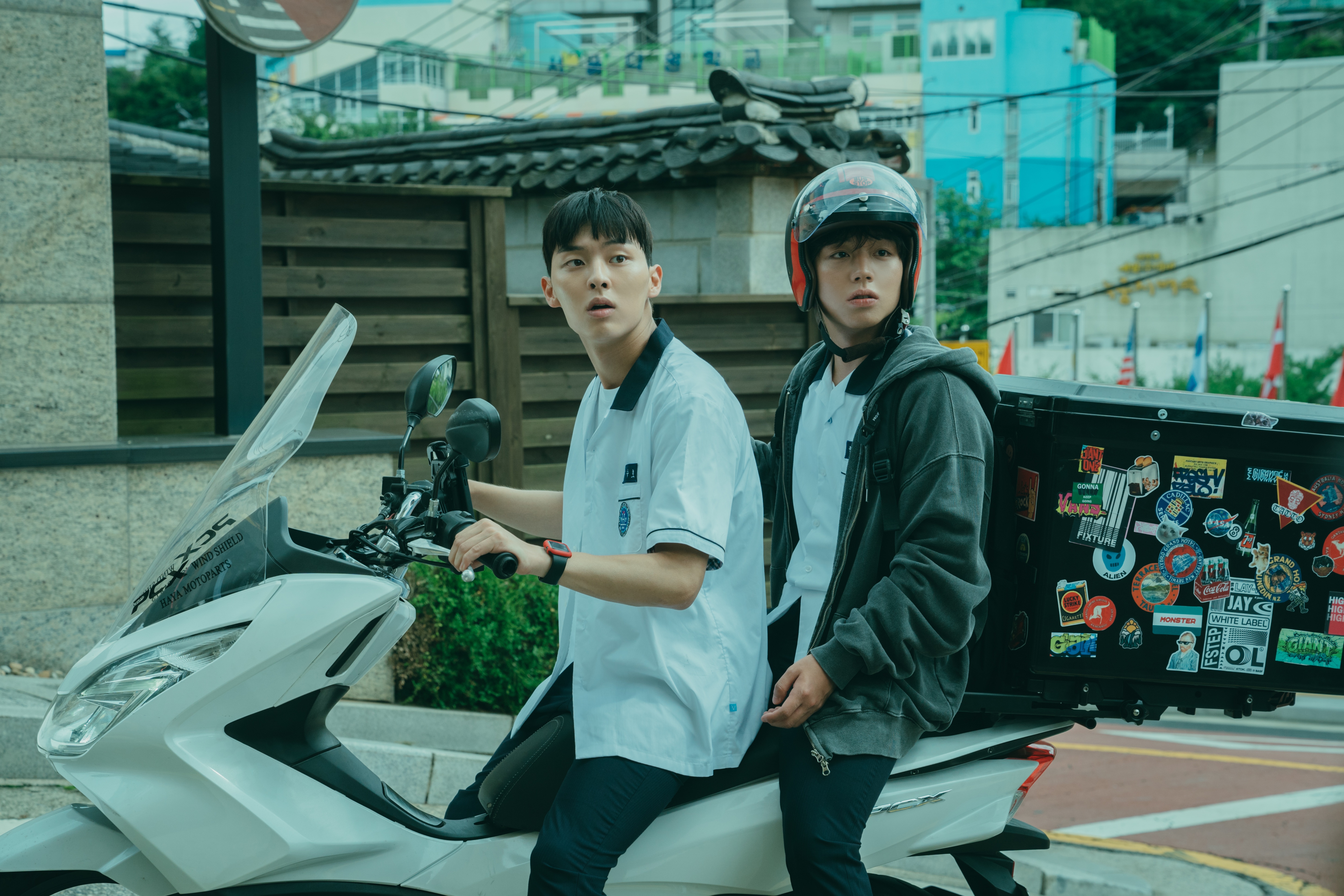 A teen in a school uniform (Choi Hyun-wook as Ahn Su-ho) drives a delivery scooter as another teen wearing a helmet (Park Ji-hoon as Yeon Si-eun) rides with him, in 'Weak Hero Class 1.'