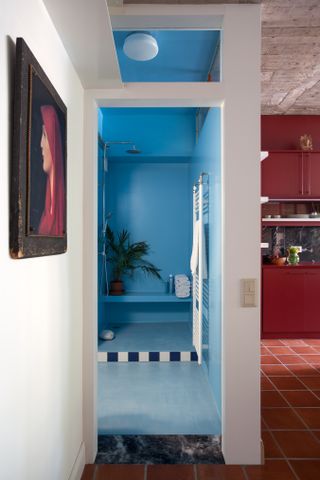 a blue bathroom next to a red kitchen