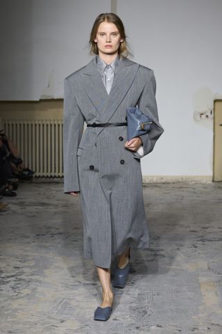Carven model wearing a great coat dress with gray mules on the SS24 runway.