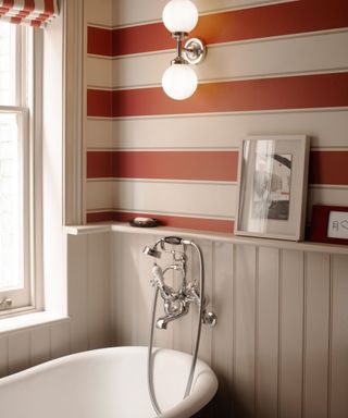 traditional bathroom with red and white striped wallpaper and a roll top with wall hung taps