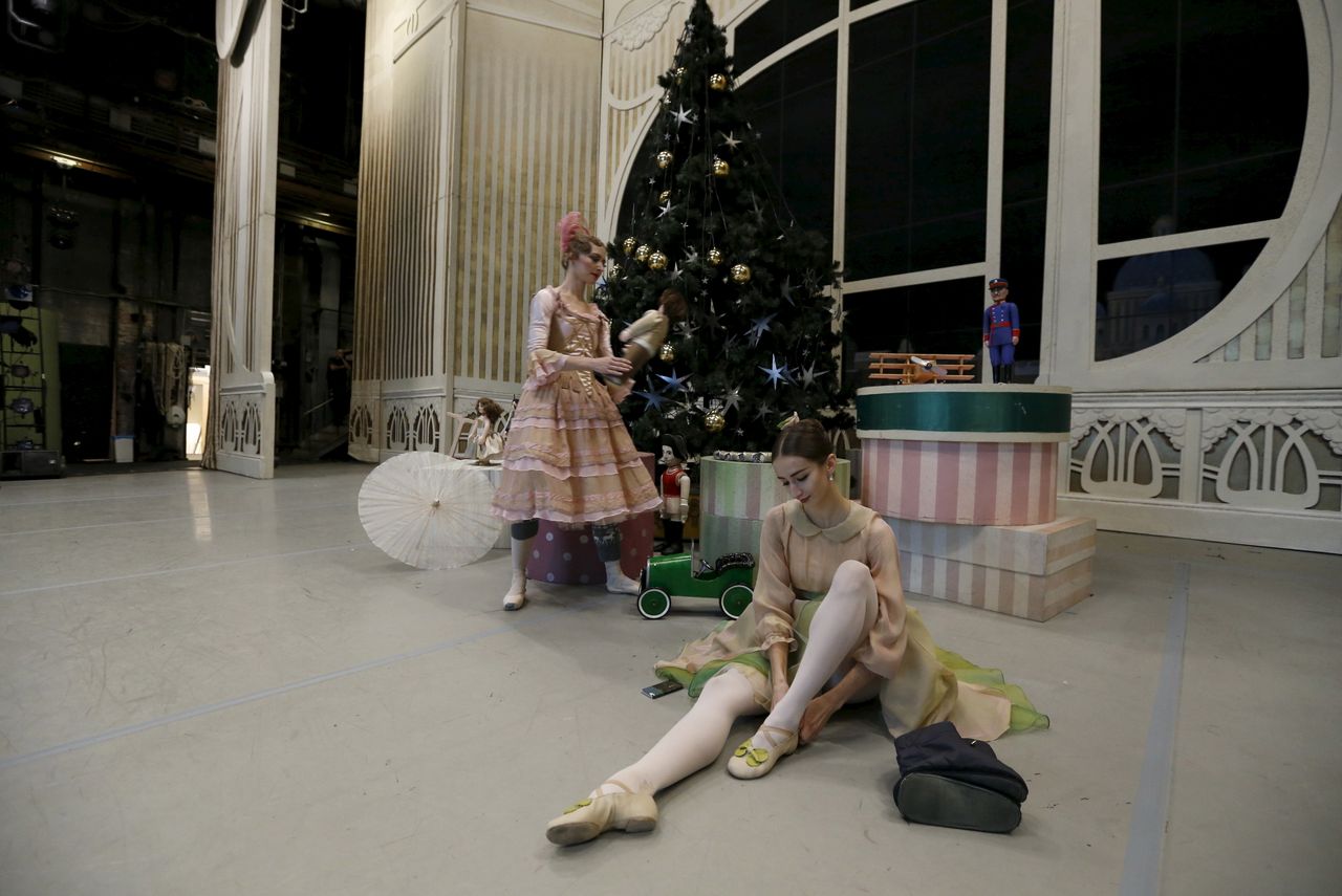 A ballet dancer puts on her shoes while sitting on a stage behind the curtain before Nacho Duato&amp;#039;s &amp;quot;The Nutcracker&amp;quot; at the Mikhailovsky Theatre in St. Petersburg, Russia.