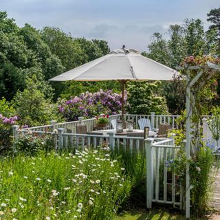 Garden terrace with meadowscaping and sun umbrella. New England Style renovation. A renovated and extended1920s country house in the New England style, in Surrey, England, home of JP Clark and husband