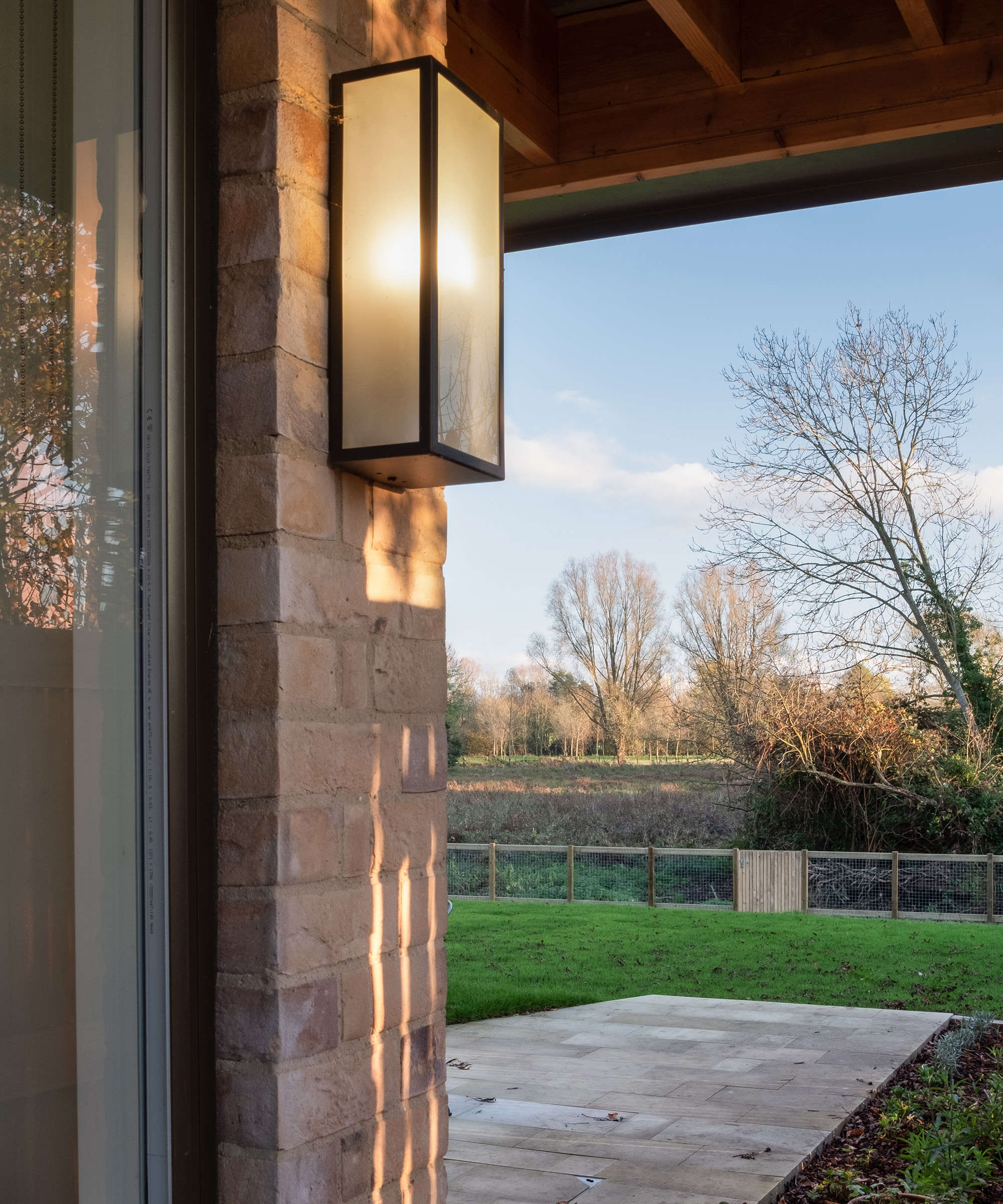 A wall light on a exterior wall with a covered veranda looking out to a garden