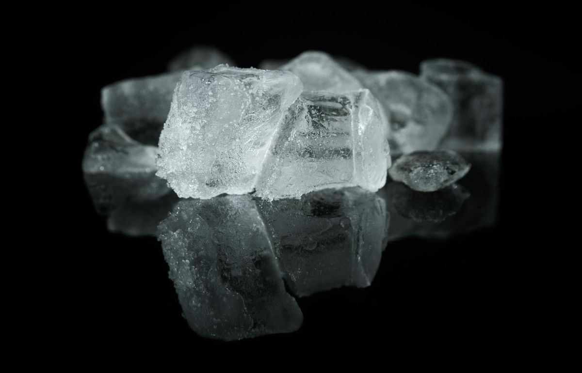 Several ice cubes on a black reflective surface